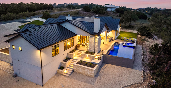 Aerial sunset view of luxury custom home with infinity pool in Spring Branch Texas