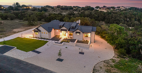 Front elevation of a custom Hill Country luxury home with metal roof and manicured lawn in Spring Branch Texas